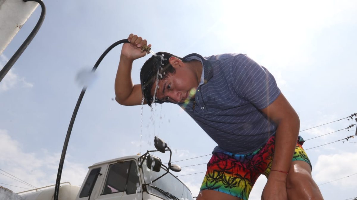 El calor hace que las personas se refresquen con agua en las gasolineras de la avenida de Las Américas,