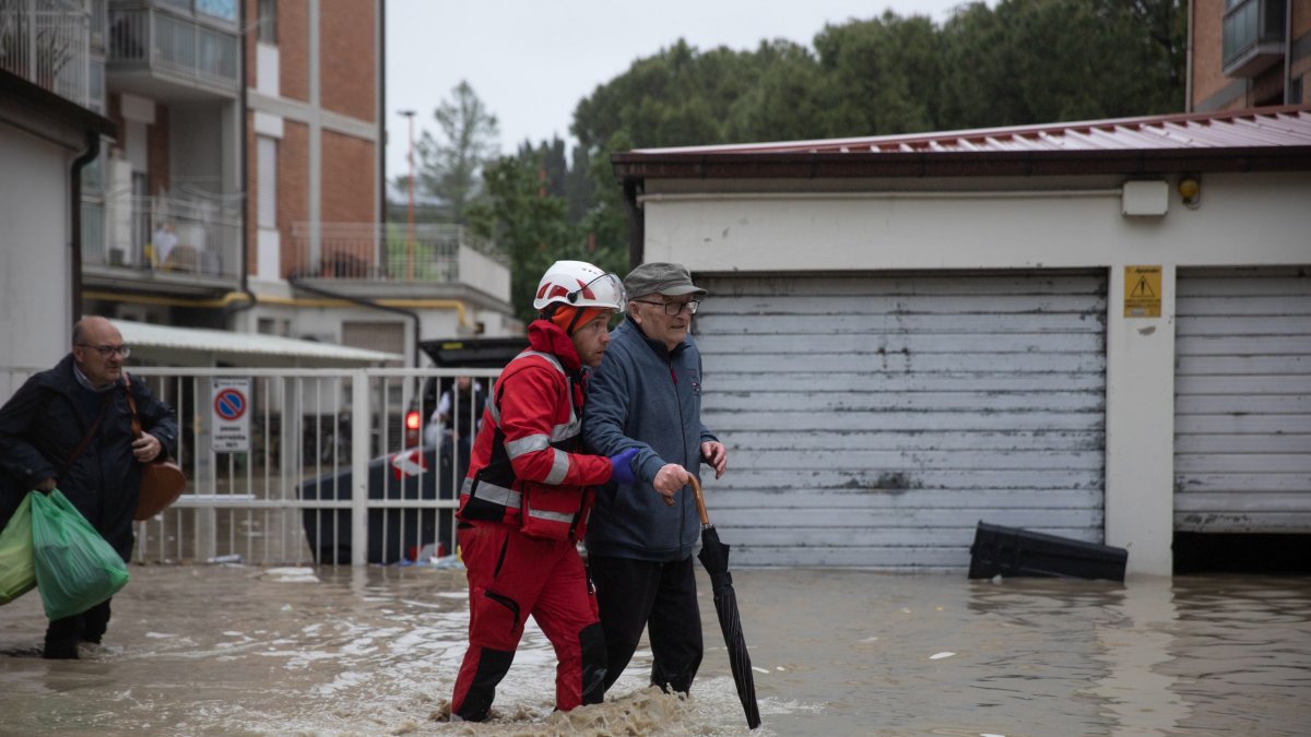 Fotografía de referencia, miembro de la Cruz Roja Italiana ayuda a las personas a salir de sus apartamentos tras crecida del río en Italia.
