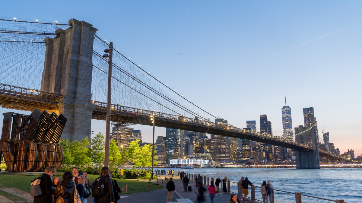 Varias personas transitan por el parque de Dumbo, ubicado a un costado del puente de Brooklyn.