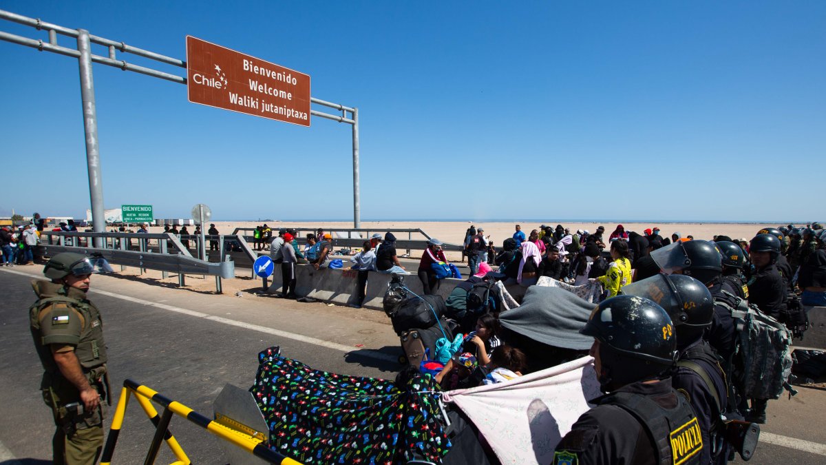 Fotografia de referencia, policías peruanos (d) y chilenos vigilan a cientos de migrantes varados en la frontera, en Arica (Chile).