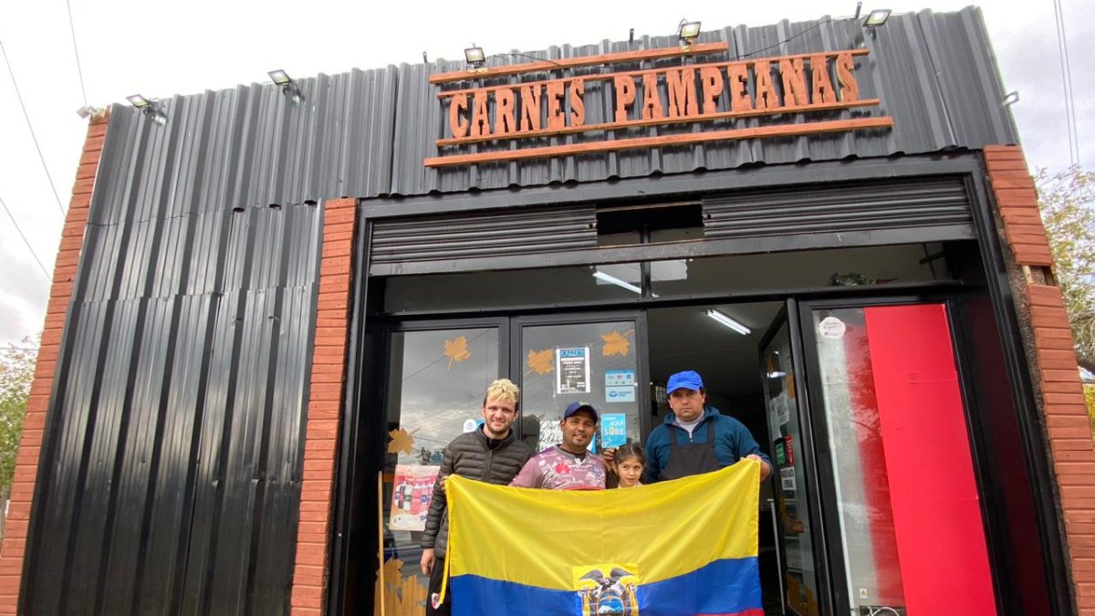 Jordy Sizalima (segundo de la izquierda) junto a dos compañeros del trabajo y una de sus dos pequeñas hijas. La carnicería lleva por nombre Pampeanas.