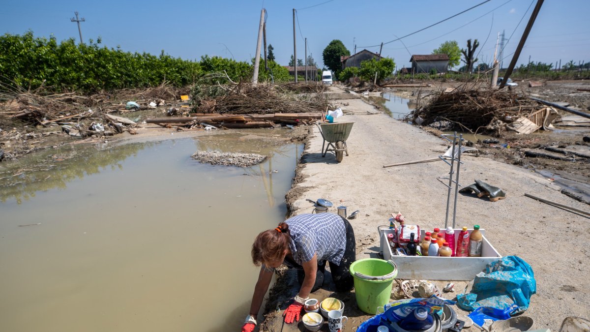 Una mujer lava vajilla en una zona inundada entre escombros, en Ca' di Lugo, un pequeño pueblo de Lugo (Ravenna), tras la crecida del río Santerno, en el norte de Italia, el 23 de mayo de 2023.