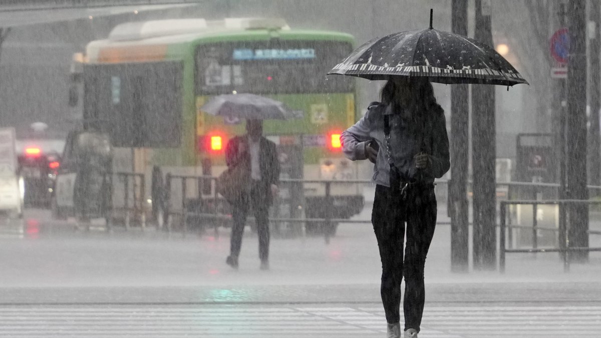 Una mujer joven camina bajo fuertes lluvias en Tokio, Japón, el 2 de junio de 2023. El aire cálido y húmedo generado por el tifón Mawar fluyó hacia el frente de la temporada de lluvias