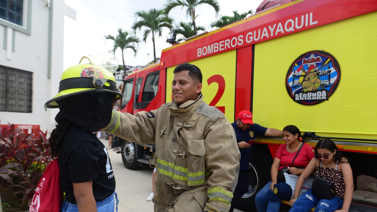 Un bombero le coloca su casco a una niña que asistió al museo.