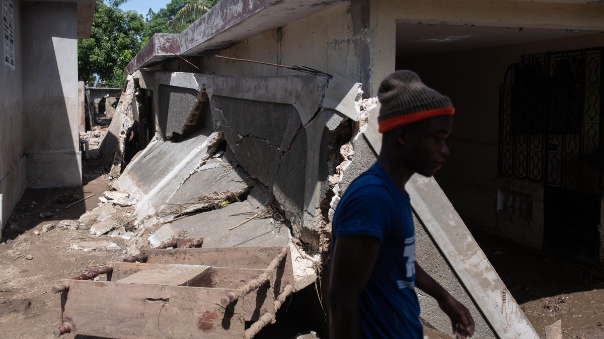 Un hombre camina junto a los escombros de una vivienda afectadas por graves inundaciones y un terremoto.