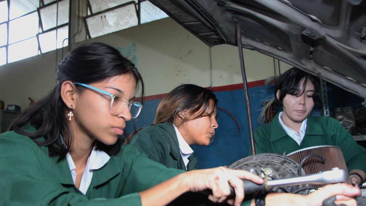 Alejandra Andrade, Mercedes Perea y Antonella Sánchez revisan el motor de un carro como parte de su aprendizaje en la especialización Electromecánica.