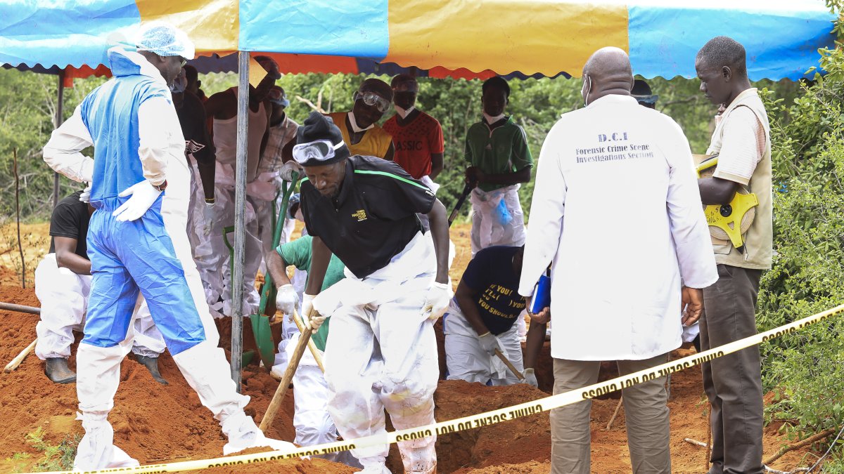 Detectives de homicidios de Kenia y expertos forenses de la Dirección de Investigaciones Criminales (DCI) examinan los cuerpos exhumados de varias fosas comunes en abril de 2023