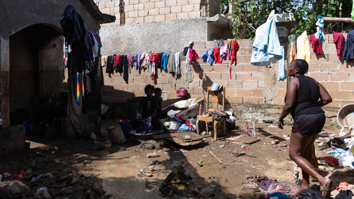 Una mujer camina entre ropa y enseres dañados por el lodo producto de las intensas lluvias en Haití.
