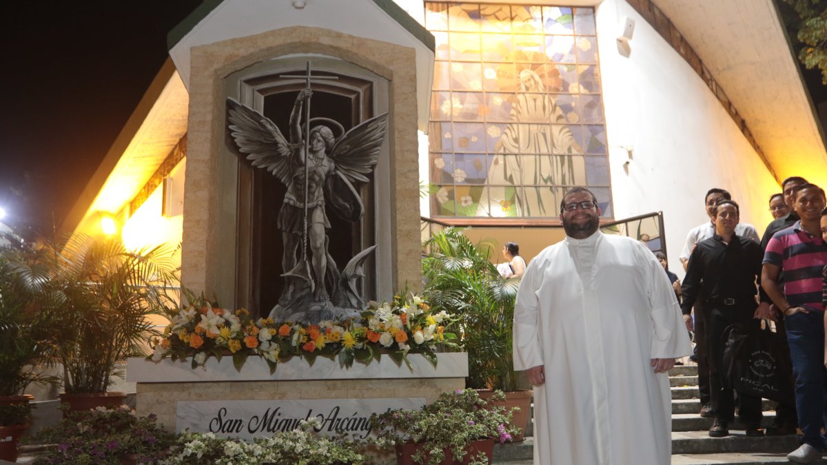 El padre Carlos Mena junto a la imagen de San Miguel.