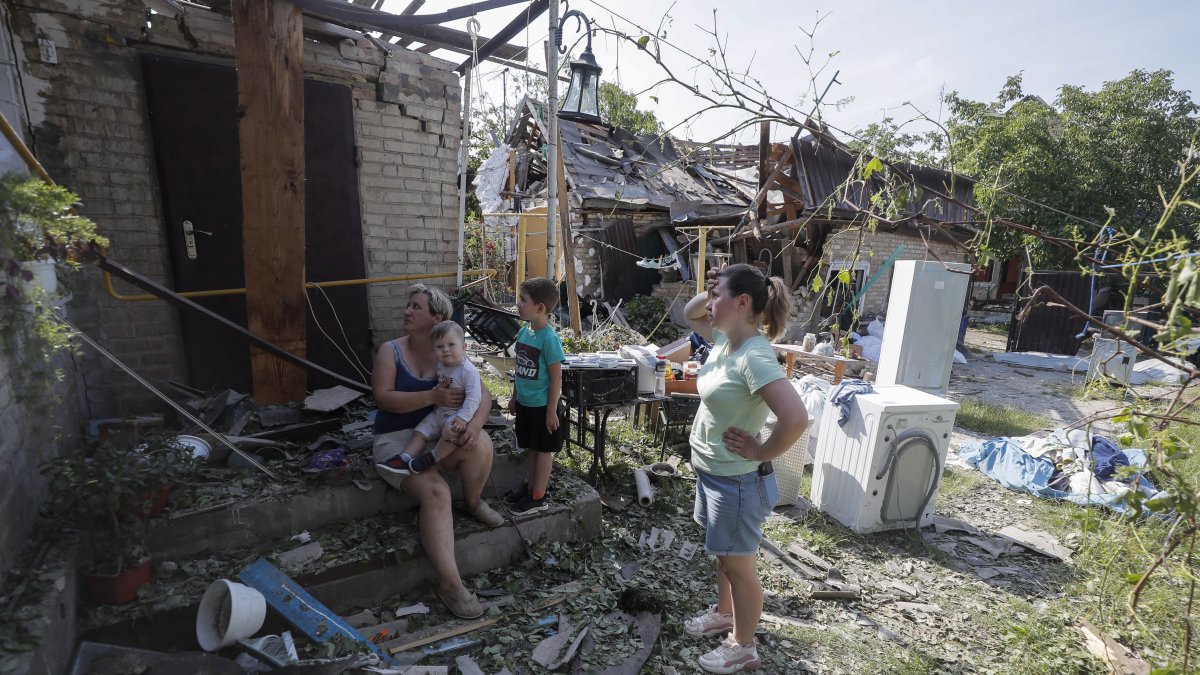 Una mujer y un niño entre los daños en el sitio alcanzado por la caída de escombros de un cohete, en la aldea de Stari Petrivtsi cerca de Kyiv (Kiev), Ucrania, el 16 de junio de 2023