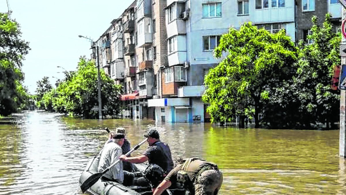 Personas se mueven en un bote inflable por las calles de la inundada ciudad de Jersón.