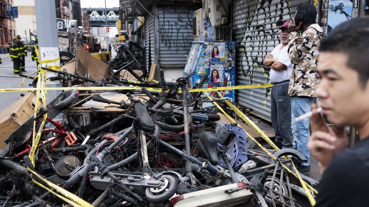 Personas observan un montón de bicicletas eléctricas quemadas cerca del lugar donde se produjo un incendio nocturno en Nueva York, este 20 de junio de 2023.