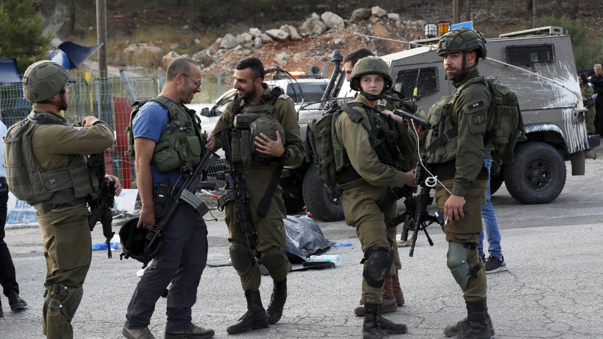 Oficiales de las fuerzas de seguridad israelíes hacen guardia junto al cuerpo de un presunto atacante  en el asentamiento de Eli, entre Nablus y Ramallah, en Cisjordania, el 20 de junio de 2023