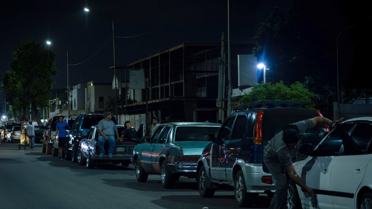 Un grupo de hombres pernoctan en una fila junto a sus vehículos mientras esperan para surtir combustible, 13 de junio de 2023, en Maracaibo (Venezuela). / Henry Chirinos