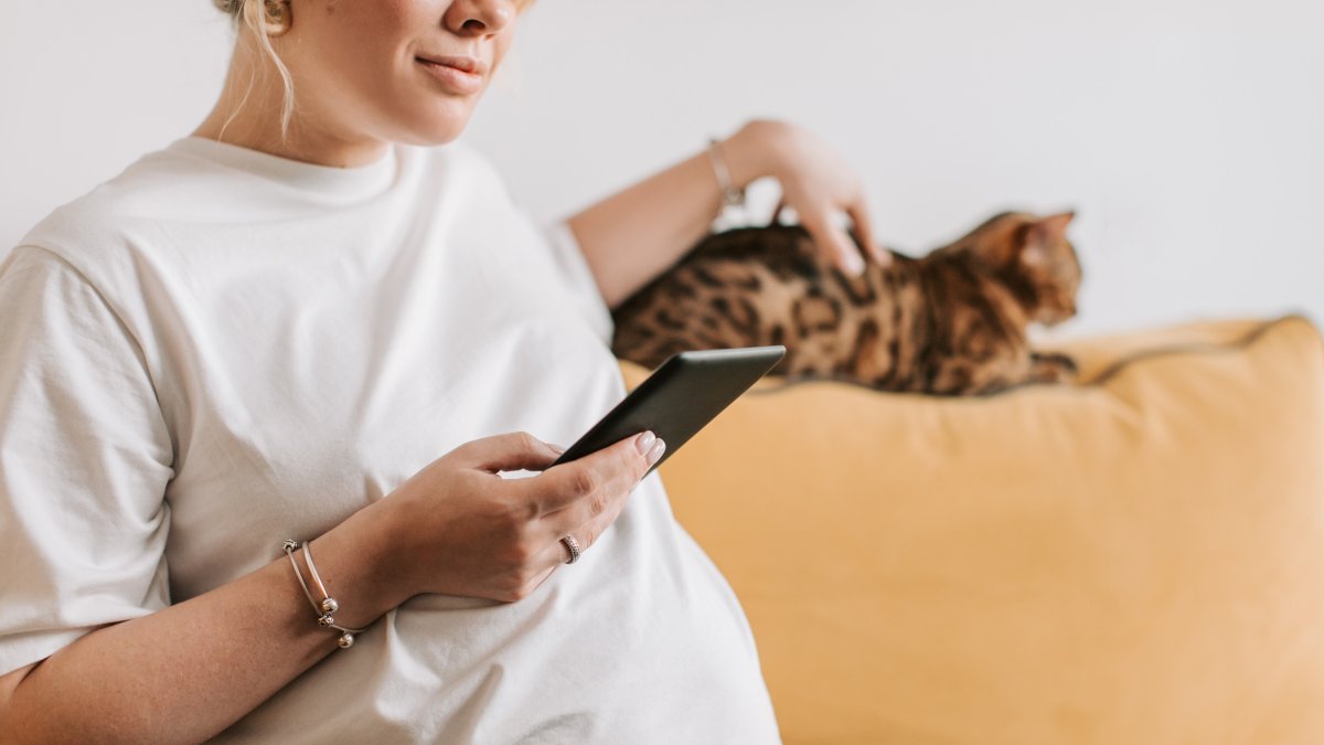 Una mujer embarazada acaricia a su gato.