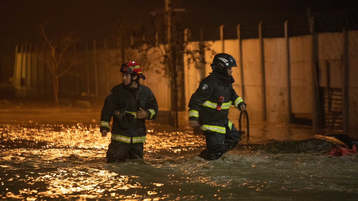 Bomberos caminan en la madrugada de hoy lunes 26 de jun de 2023  por calles anegadas por agua tras la crecida del río Cachapoal, producto de las intensas lluvias en la comuna de Coltauco (Chile).