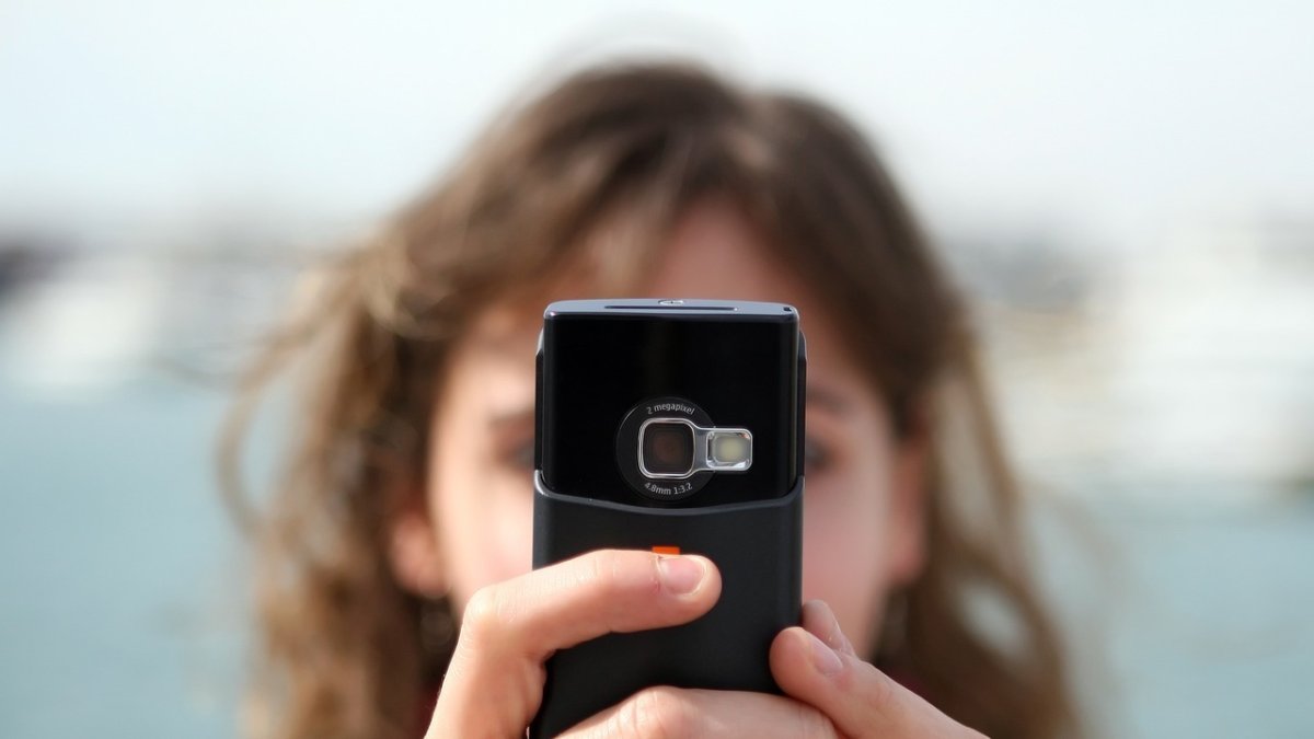 Telecomunicación.- Una persona usa su celular para enviar un mensaje escrito.