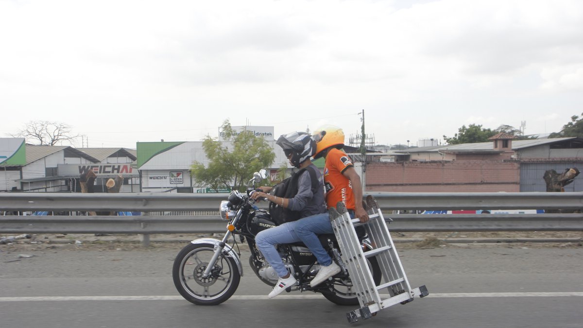 Ocupantes de moto movilizan una escalera metálica.