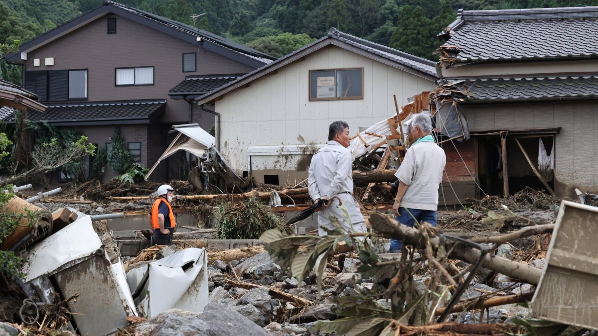 Personas observan los daños sufridos en las casas por las inundaciones y deslizamientos causados por las lluvias en Kurume, Japón.