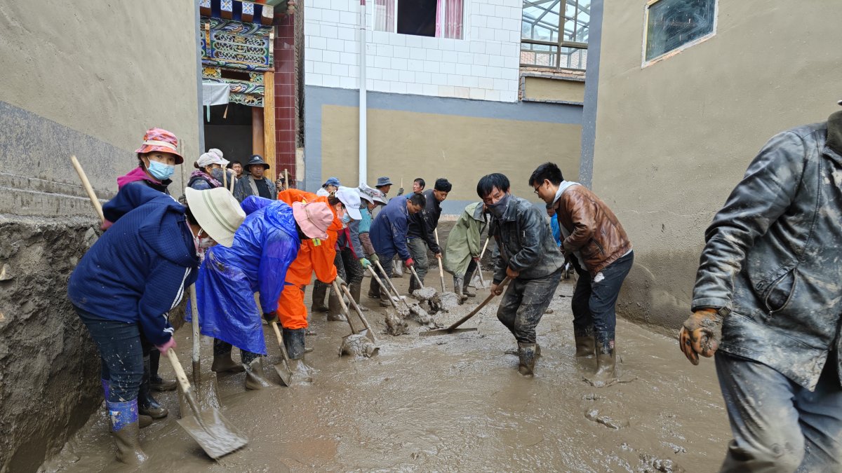 Moradores de la aldea de limpian los escombros de un deslizamiento de tierra en una zona de Zhangzigou.