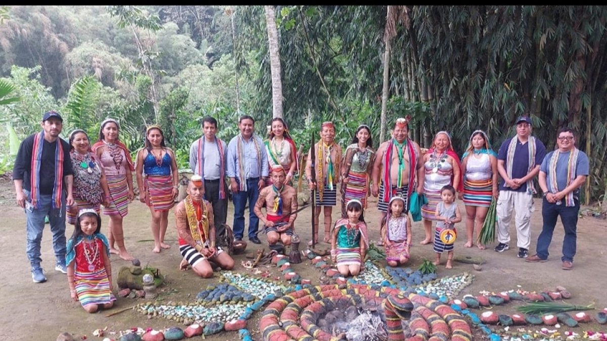 Un grupo de personas aparecen rodeando una instalación tradicional en la nacionalidad Tsa'chila.