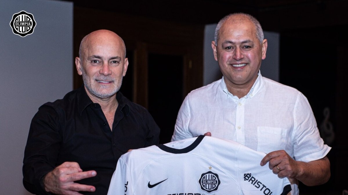 Francisco Arce (d) posa ante las cámaras tras estampar su firma como seleccionador del Olimpia junto al presidemte del club Miguel Cardona.