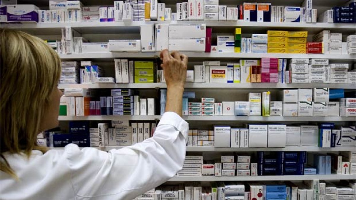 Imagen referencial. Una dependiente de una farmacia revisa los medicamentos en las perchas.