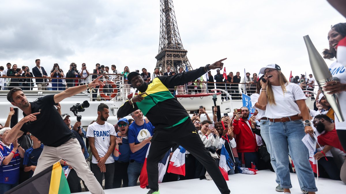 El velocista retirado jamaiquino Usain Bolt (c) compartió con dirigentes del comité organizador y deportistas en el acto del inicio del conteo regresivo frente a la Torre Eiffel.
