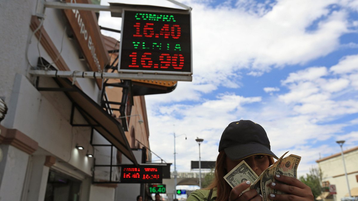 Divisa.- Una mujer muestra los dólares frente a la casa de cambios.