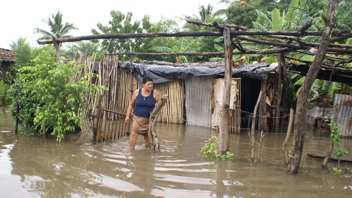 En la imagen un registro de archivo de una mujer frente a su casa inundada en el municipio de Monjaras (sur de Honduras).