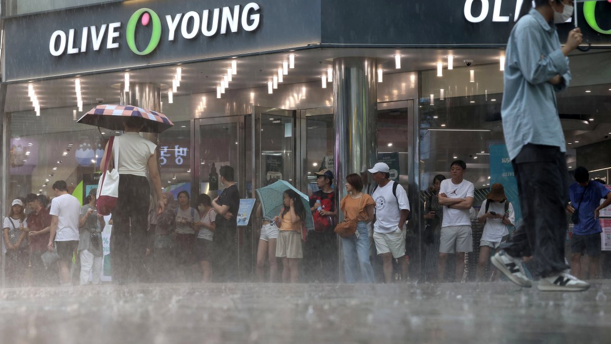 Turistas extranjeros se ven atrapados en una lluvia repentina en la calle Myeongdong en Seúl, Corea del Sur, el 31 de julio de 2023, en medio de una alerta de ola de calor.