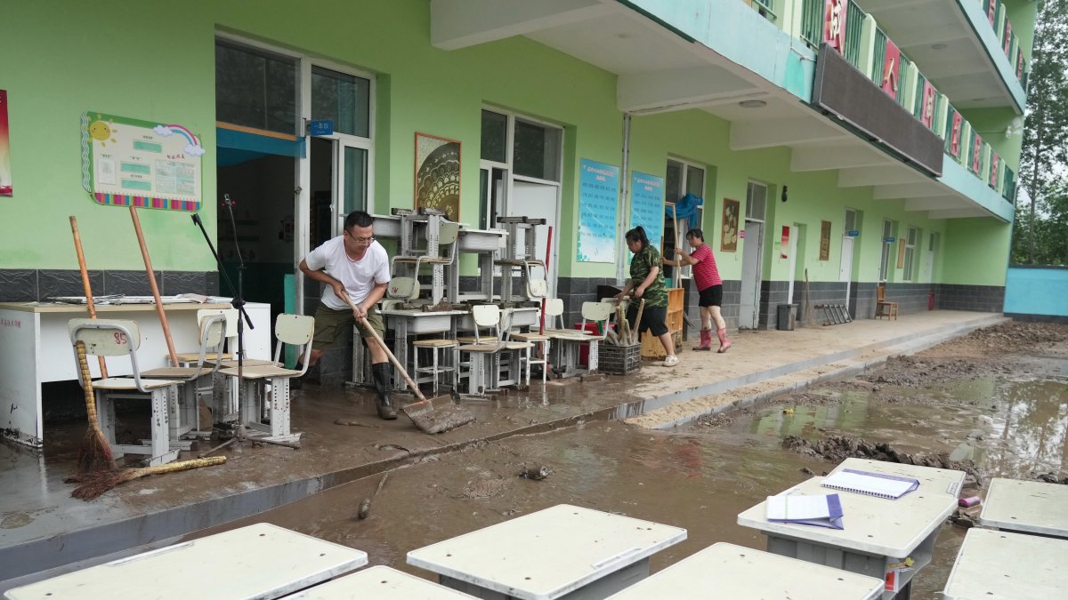 Profesores limpian el agua acumulada en el pueblo de Qizhongkou en la provincia de Hebei.