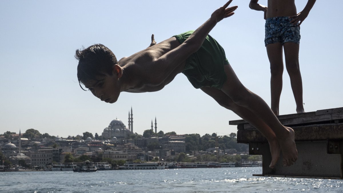 En la imagen de archivo, una persona se sumerge en las aguas del Bósforo para refrescarse, con la mezquita de Süleymaniye al fondo, en Estambul, Turquía.