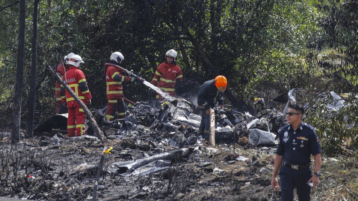 Oficiales del Depmento de Bomberos y Rescate de Malasia inspeccionan la escena del accidente de una avioneta en Elmina, estado de Selangor, Malasia. 