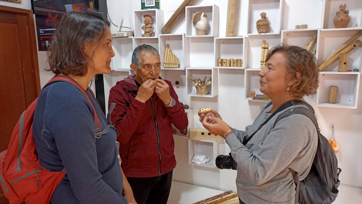 Artesanías. Adolfo Idrovo, investigador y artesano enseña a dos turistas, sus habilidades con los silbatos.