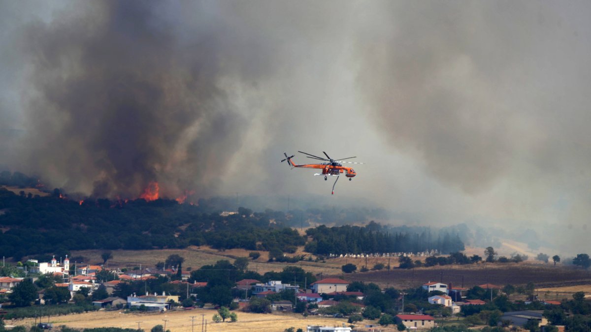 Un helicóptero contra incendios sobrevuela la zona afectada por un incendio forestal cerca del puerto de Alexandroupolis, Grecia, este domingo 20 de agosto.