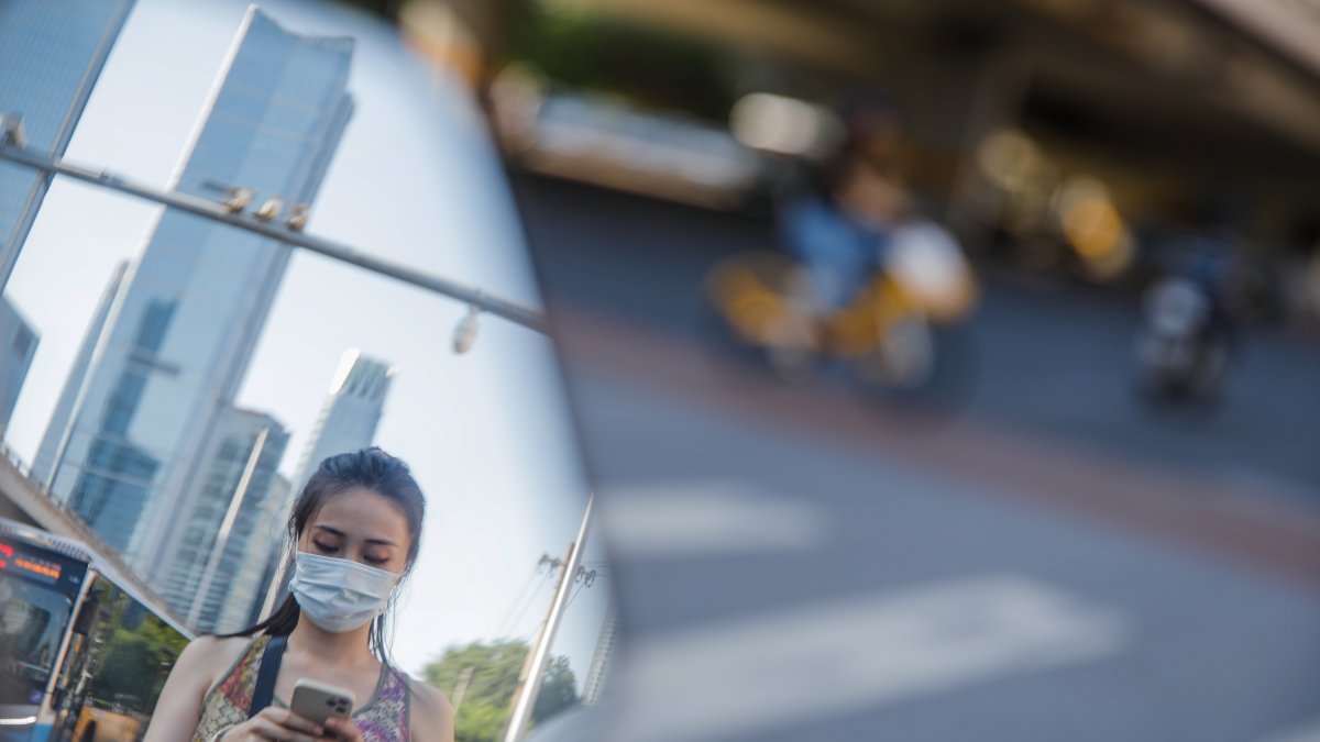 Una mujer con mascarilla camina por una calle de Pekín, China, estel 21 de agosto de 2023.  