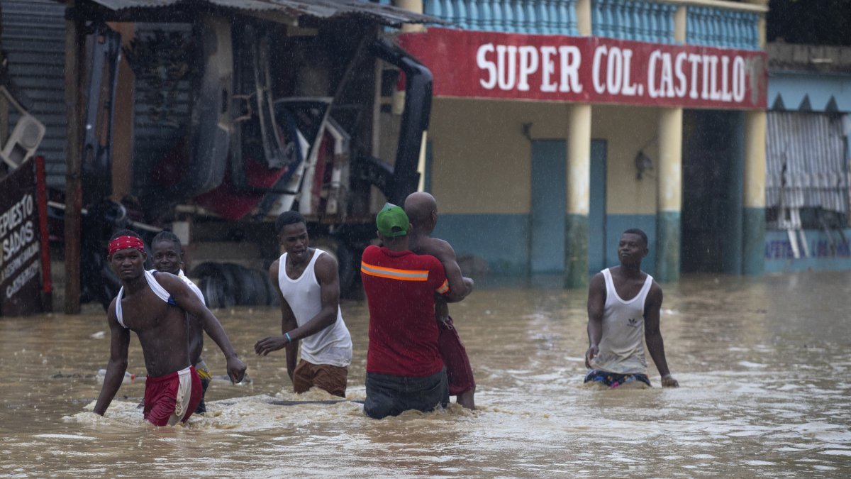Personas caminan por calles inundadas de Santo Domingo debido al paso de la tormenta tropical Franklin.