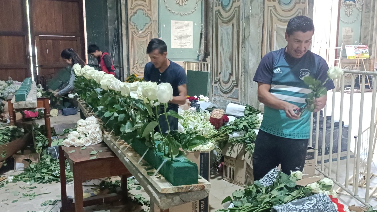Voluntarios colocan cuidadosamente las flores donadas.
