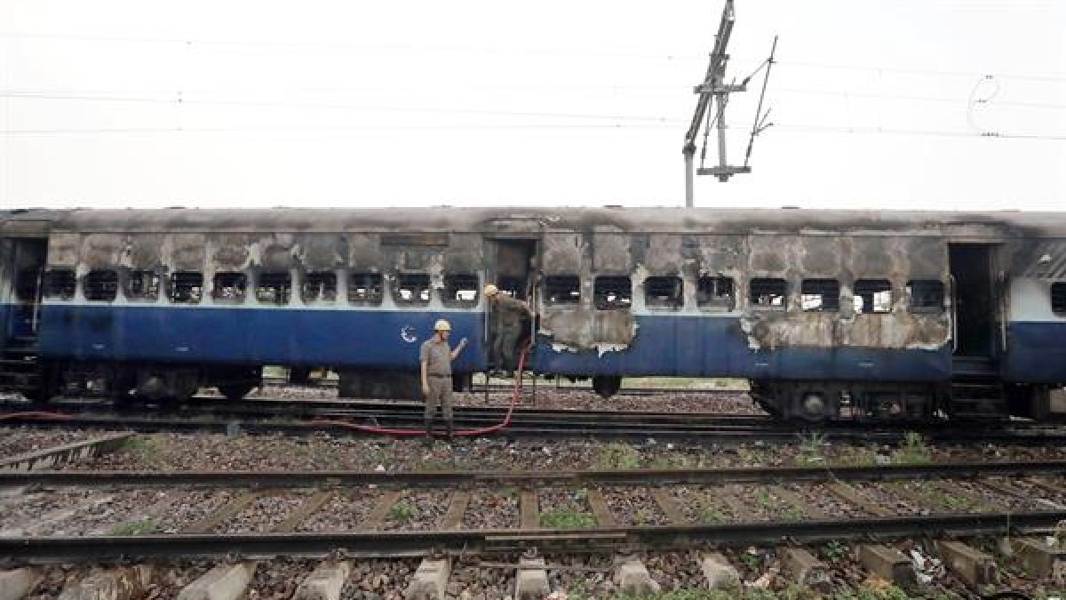 Bomberos indios terminan de extinguir el fuego de un vagón de tren.