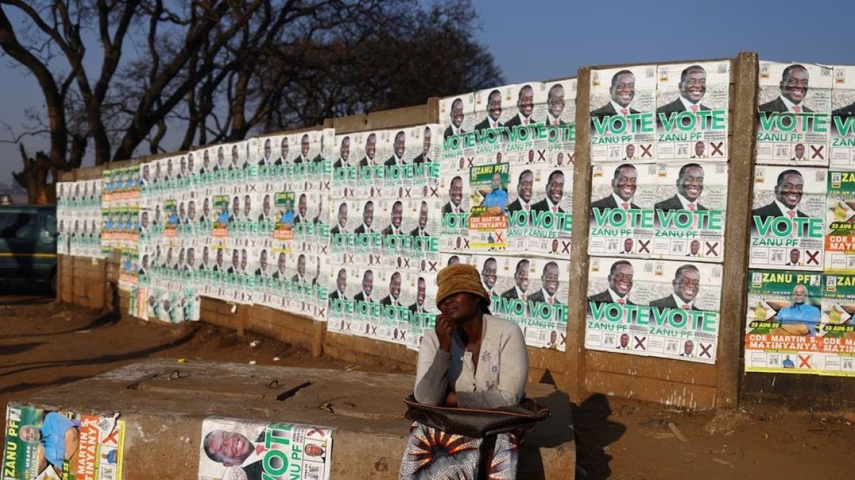 Una mujer posa junto a las imágenes de candidatos en el barrio de Mbare, en Harare, el 21 de agosto.