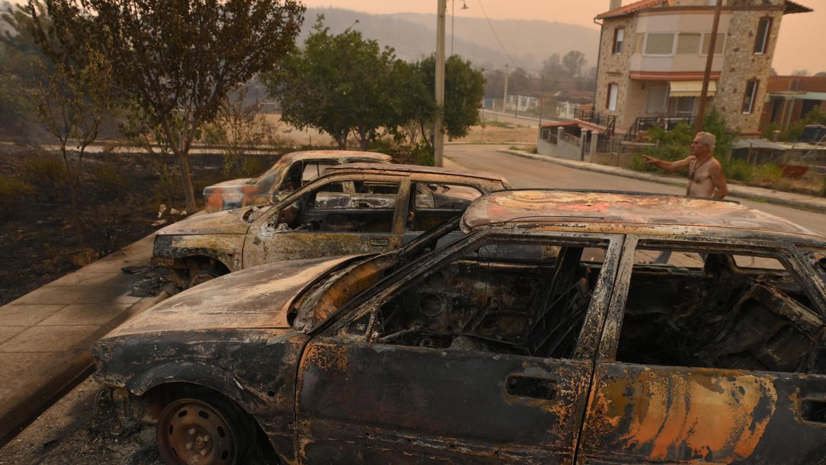 Un hombre señala coches quemados durante un incendio forestal, en la aldea de Palagia, Alejandrópolis, Tracia, en el norte de Grecia.