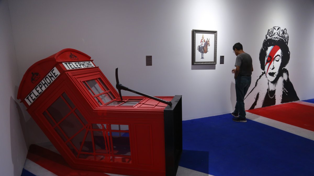 Visitantes observan obras del artista británico Banksy durante la exposición 