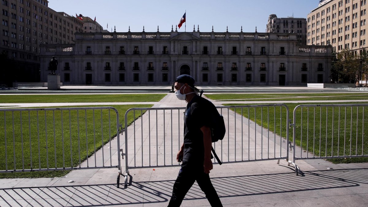 Un hombre camina usando mascarilla frente al Palacio de la Moneda, en Santiago.
