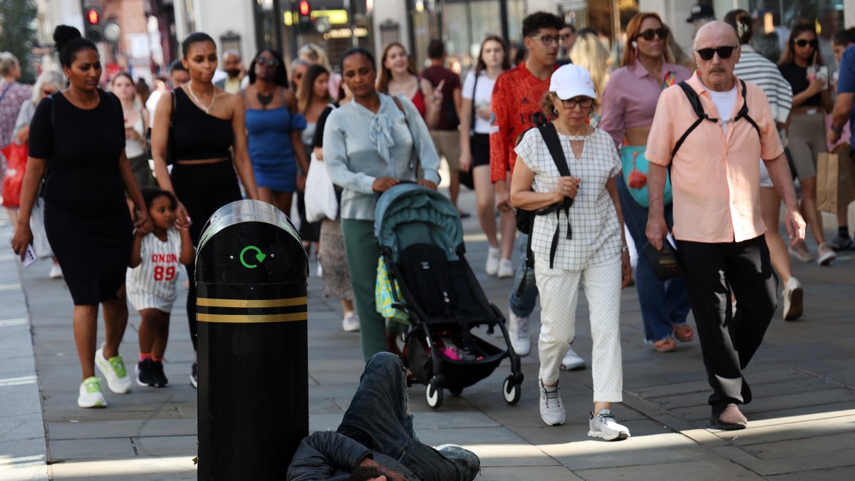 Un hombre sin hogar en la calle Oxford de Londres rodeado de transeúntes, hoy 5 de septiembre de 2023.