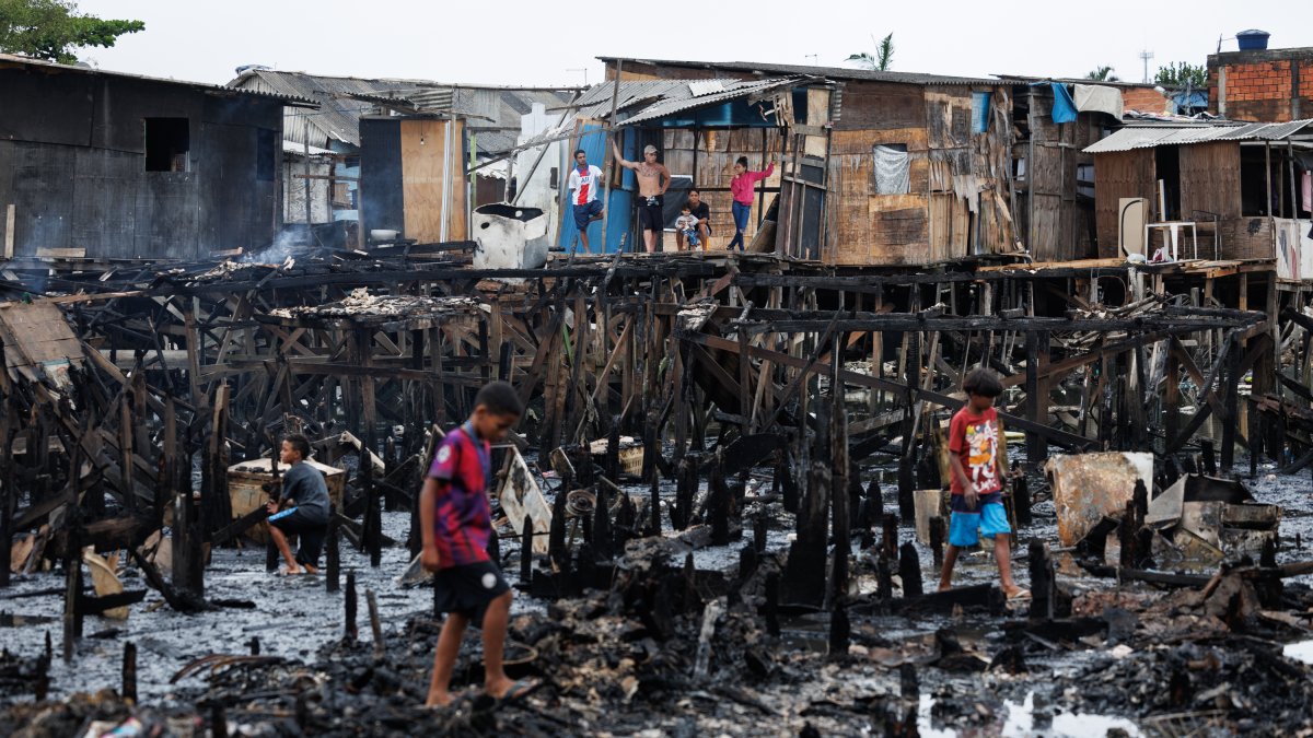 Personas observan los restos y buscan objetos tras un incendio de grandes proporciones que destruyó más de 100 viviendas de madera construidas sobre palafitas, este 5 de septiembre en Santo (Brasil). 