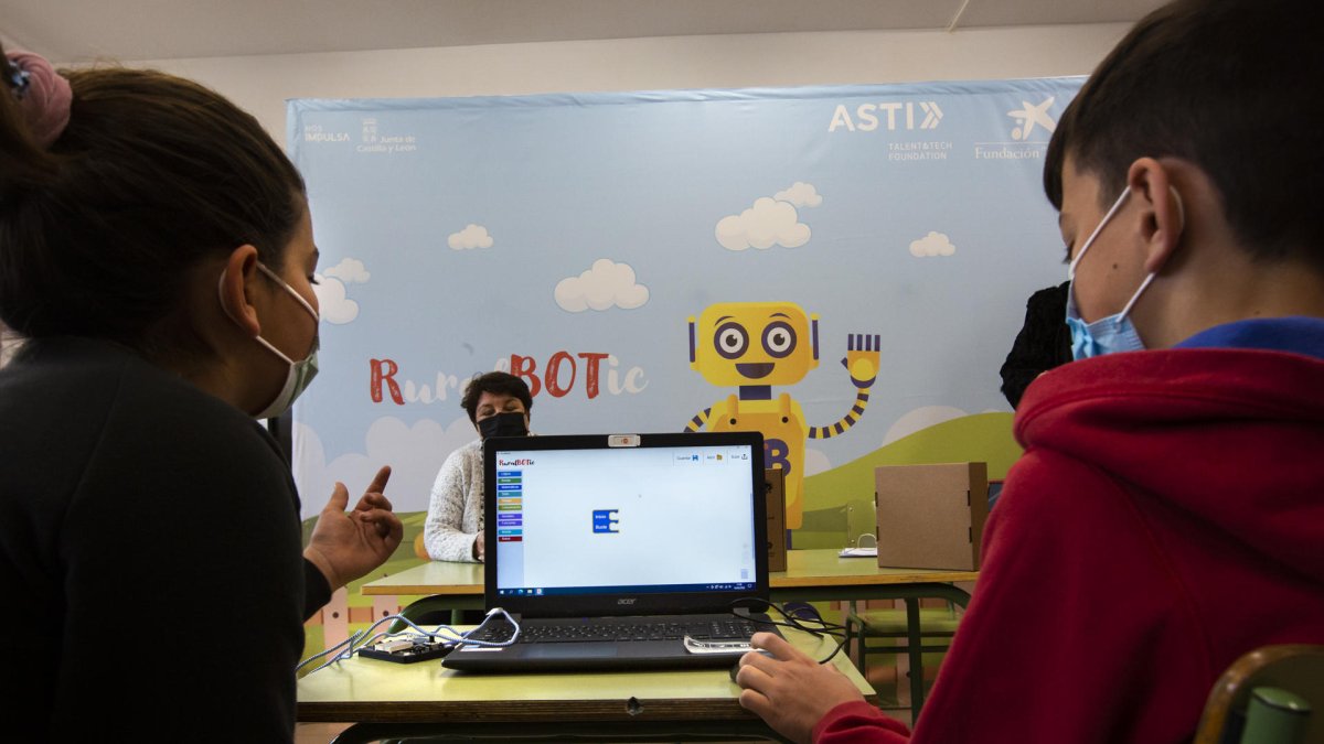 Dos niños manejan un robot por ordenador en un colegio español.