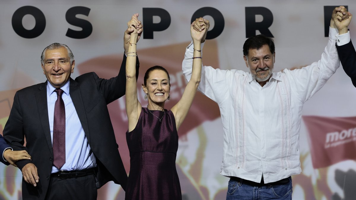 El exsecretario de Gobernación, Adán Augusto López (i) y el diputado Gerardo Fernández Noroña (d) levantan la manos a Claudia Sheinbaum (c) tras ser designanada como candidata presidencial.