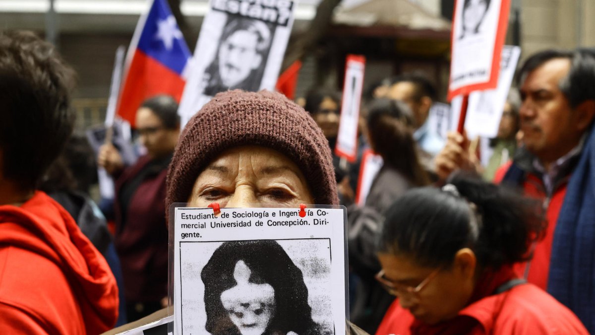Una mujer muestra el retrato de un desaparecido en la dictadura de Augusto Pinochet.