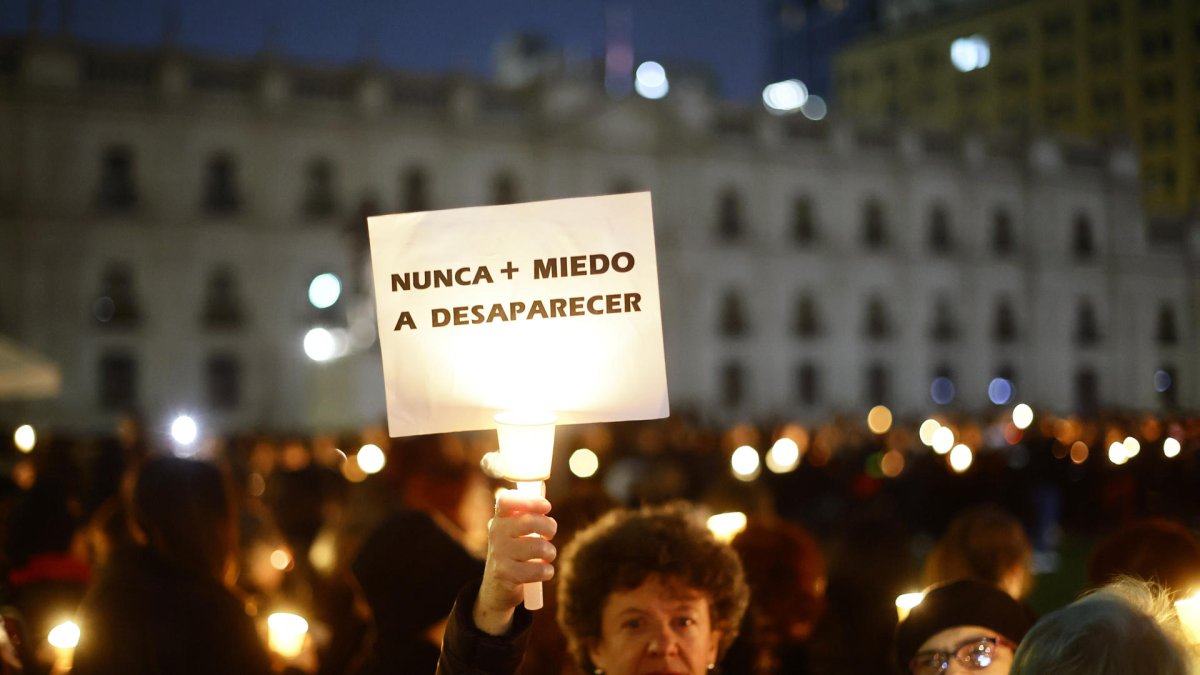 Una mujer levanta un cartel en rechazo a la dictadura de Augusto Pinochet.
